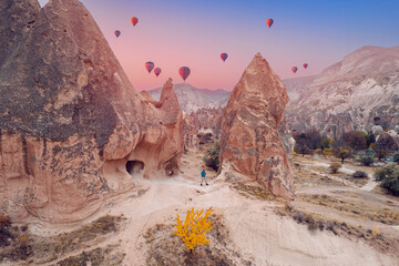 Wall Mural - Young hiker man in hat on top mountain background hot air balloons and Cave house in Cappadocia Turkey travel, aerial top view