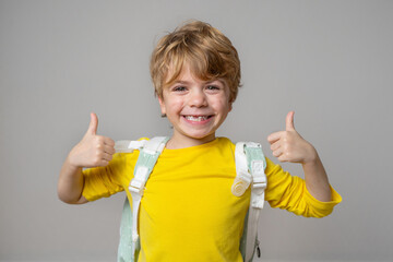 Primary school smiling boy girl over grey background with backpack showing thumbs up. Copy space for advertising blank concept. Back to school. Childhood, education, products for children