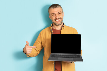 Poster - Happy mature caucasian man showing laptop computer empty screen, recommending website, mockup