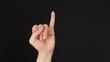 Little finger or pinkie gesture hand sign on black background.