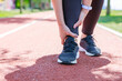 Injury from workout: Young woman use hands hold on her ankle while running on track field..