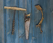 Three rusty basic hand tools hanging on blue wooden wall