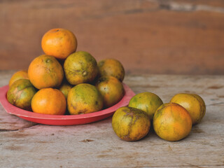 Oranges in a red dish on the wooden table