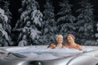 © ronstik - happy couple relaxing in outdoor jacuzzi at winter in resort spa hotel. romantic getaway