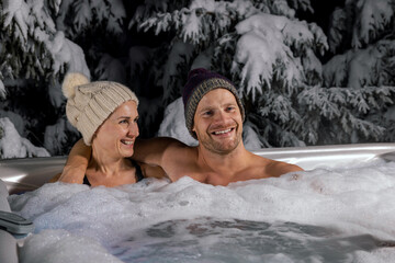 Wall Mural - young couple relaxing in outdoor hot tub in winter