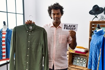 Sticker - African man with curly hair holding black friday banner at retail shop skeptic and nervous, frowning upset because of problem. negative person.