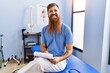 © Krakenimages.com - Young redhead man wearing physiotherapist uniform writing medical report at physiotherapy clinic