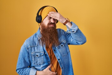 Poster - Caucasian man with long beard listening to music using headphones touching forehead for illness and fever, flu and cold, virus sick