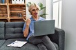© Krakenimages.com - Young man working using computer laptop sitting on the sofa pointing thumb up to the side smiling happy with open mouth