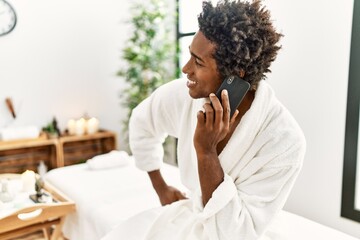 Wall Mural - Young african american man smiling confident talking on the smartphone at beauty center