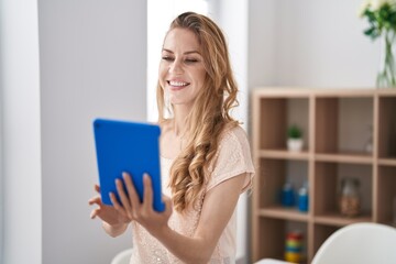 Wall Mural - Young blonde woman smiling confident using touchpad at home