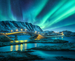 Wall Mural - bridge and northern lights over snowy mountains. lofoten islands, norway. aurora borealis and reflec