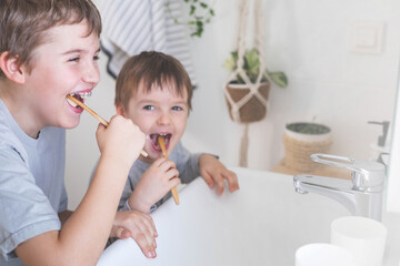 Brother morning fun male kids cleaning teeth toothbrush in front of mirror sink at bathroom