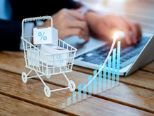 Online Shopping Purchase, Sales Increase, Market Trends Concepts. Rising Arrow On Business Growth Graph Near The Shopping Cart Trolley With Parcel Boxes On Desk Near Person Using Laptop Computer.