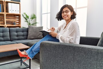 Canvas Print - Young hispanic therapist woman working at consultation office smiling happy pointing with hand and finger