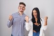 © Krakenimages.com - Young hispanic couple standing over white background celebrating surprised and amazed for success with arms raised and eyes closed. winner concept.