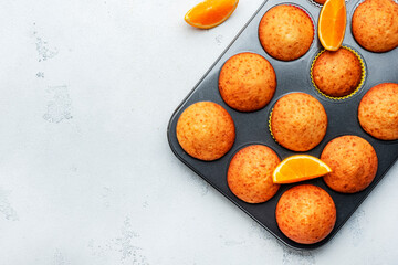 Appetizing orange muffins or cupcakes on white table background, winter homemade pastries, top view