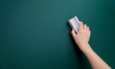 Wall Mural - Hand holding brush erase on blackboard