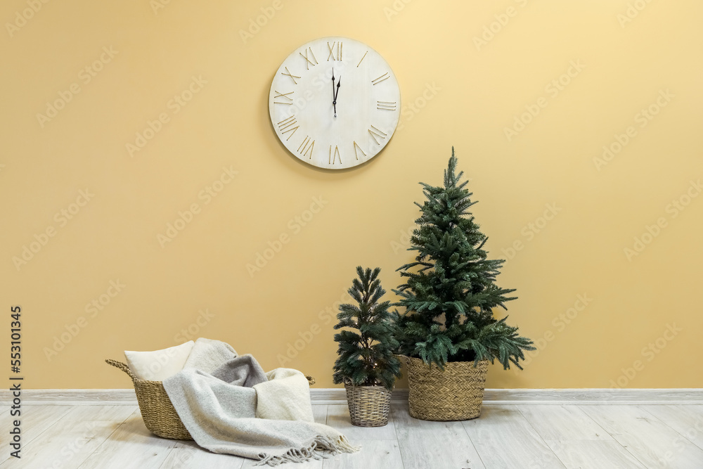 Basket with plaid, Christmas trees and big clock hanging on beige wall
