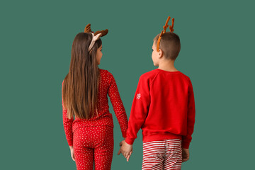 Poster - Little children in pajamas holding hands on green background, back view