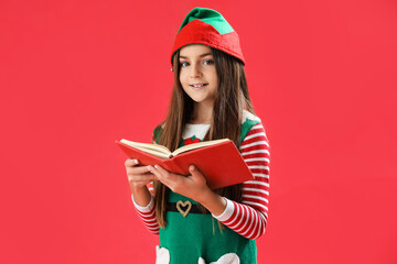 Poster - Little girl in elf pajamas with book on red background