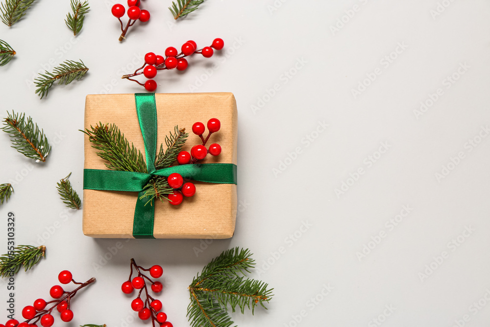 Christmas gift box with fir branches and viburnum on grey background