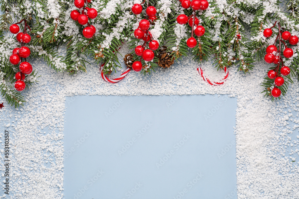 Frame made of snow, Christmas branches and rowan on blue background