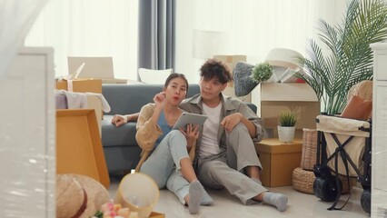 Wall Mural - Young happy Asia couple sit on sofa couch use digital tablet online shopping furniture from decoration store in living room at home. Husband wife move new house, Apartment Rent And Ownership Concept.