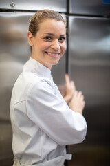 female chef stood by stainless-steel industrial fridge