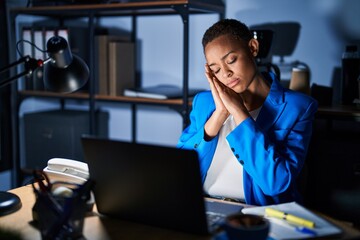 Poster - Beautiful african american woman working at the office at night sleeping tired dreaming and posing with hands together while smiling with closed eyes.