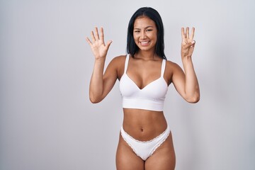 Poster - Hispanic woman wearing lingerie showing and pointing up with fingers number eight while smiling confident and happy.