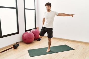 Wall Mural - Young hispanic man stretching at sport center