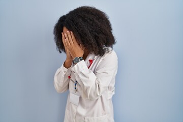 Poster - Young african american woman wearing doctor uniform and stethoscope with sad expression covering face with hands while crying. depression concept.