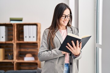 Poster - Young woman psychologist smiling confident reading book at psychology center