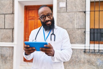 Poster - Young african american man wearing doctor uniform using touchpad at hospital