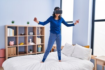 Sticker - Young latin woman using virtual reality glasses standing on bed at bedroom