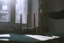Woman burning candle on fir wreath at home in Christmas