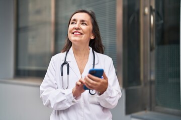 Sticker - Middle age woman wearing doctor uniform using smartphone at street