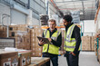 © Jacob Lund - Warehouse workers using a digital tablet while recording inventory