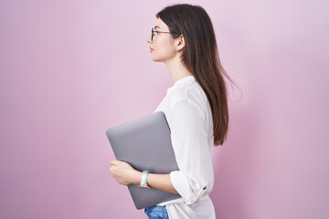 Sticker - Young caucasian woman holding laptop looking to side, relax profile pose with natural face and confident smile.