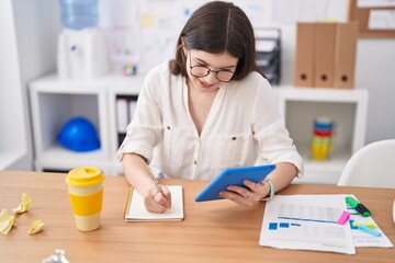 Poster - Young caucasian woman business worker talking on smartphone writing on notebook at office