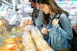 © PR Image Factory - Asian American woman buying sliced fruit on the street. side view lady shopping in the supermarket. authentic lifestyle.
