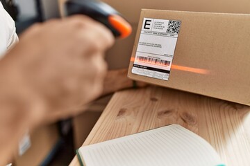 Wall Mural - Young hispanic man scanning package label with barcode reader at storehouse