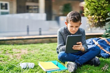 Poster - Blond child using touchpad sitting on grass at park