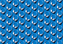 Pattern Of Rows Of Headphones Flat Laid Against Blue Background