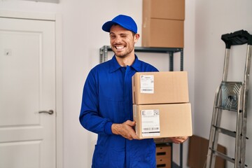 Poster - Young hispanic man working on moving service holding boxes winking looking at the camera with sexy expression, cheerful and happy face.