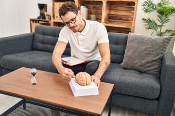 Wall Mural - Young hispanic man psychology holding brain at psychology center