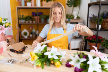 Poster - Young blonde woman florist smiling confident holding gift lace at flower shop