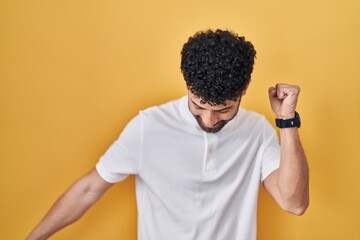 Sticker - Arab man standing over yellow background dancing happy and cheerful, smiling moving casual and confident listening to music