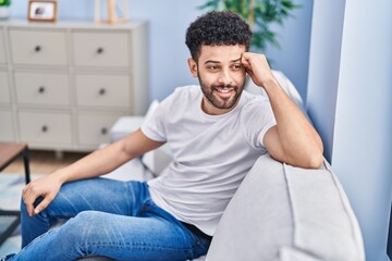 Sticker - Young arab man smiling confident sitting on sofa at home